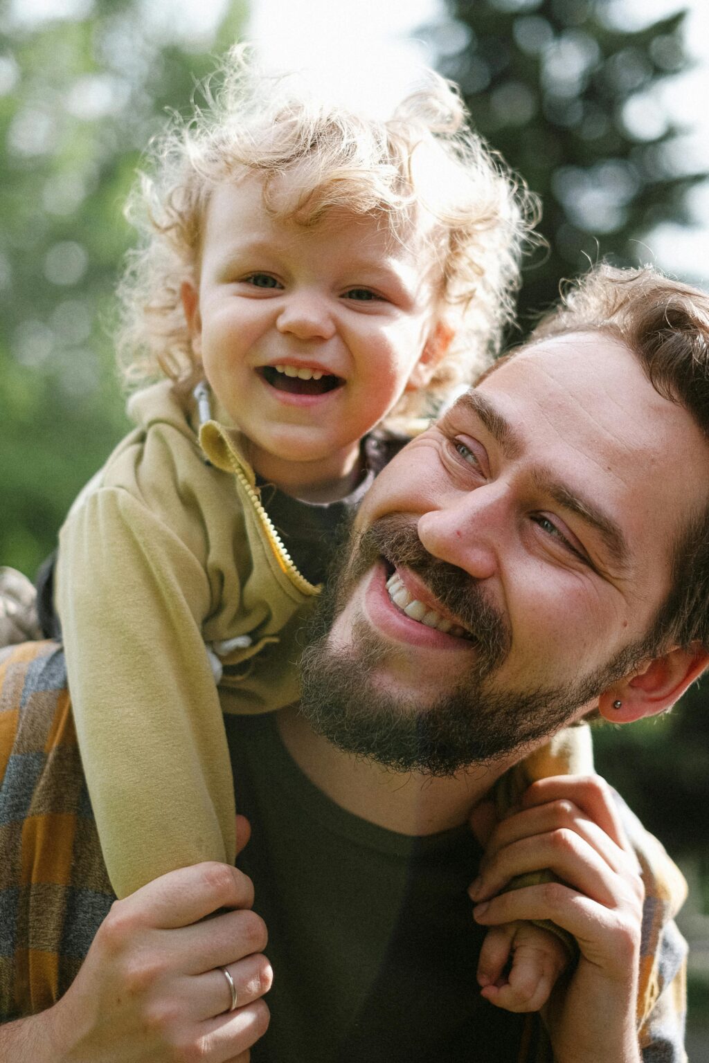 A joyful moment captured with a father and his son smiling in an outdoor setting.